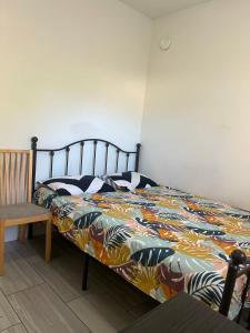 a bed with a colorful comforter and a wooden chair at 3 bedroom 2 bathroom garden suite in Victoria