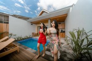 two young women standing on a patio next to a swimming pool at Sunrise Cottage in Nusa Penida