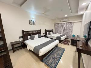 a bedroom with two beds and a flat screen tv at Hotel Misty Meadows by Vanyum in Pachmarhī