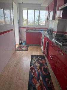 a kitchen with red cabinets and a stove top oven at Blu capri in Dar Bouazza