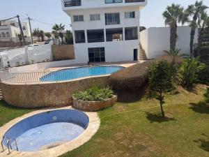 a swimming pool in a yard in front of a building at Blu capri in Dar Bouazza