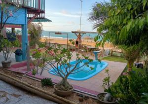 a swimming pool in a yard with the ocean in the background at Chalés Panulirus in Icapuí