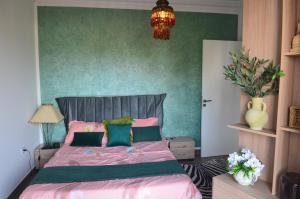 a bedroom with a bed with pink sheets and green walls at L'Appartement La Roche Élégance et confort in Banzart