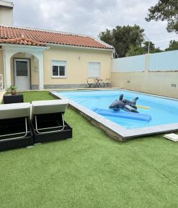a large swimming pool with a man laying on the grass at Cozy House in Charneca