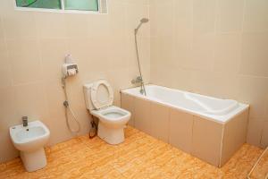 a bathroom with a toilet and a bath tub and a bidet at Visitors Inn Zanzibar in Jambiani +33 photos