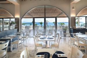 a restaurant with tables and chairs and windows at Akrathos Beach Hotel in Ouranoupoli