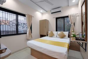 a bedroom with a bed and two windows at Hotel Royal Comforts in Pune