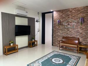 a living room with a tv and a bench and a brick wall at singgah homestay yala2 in Ban Sarong