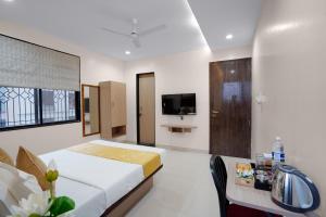 a bedroom with a bed and a table and a tv at Hotel Royal Comforts in Pune +24 photos
