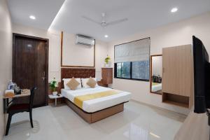 a bedroom with a bed and a desk and a television at Hotel Royal Comforts in Pune