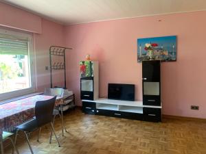 ein Wohnzimmer mit rosa Wänden, einem Tisch und einem Fernseher in der Unterkunft Haus Tun in Waldbröl