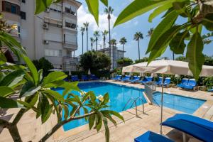 a pool at a hotel with blue chairs and palm trees at Miray Hotel Kleopatra in Alanya