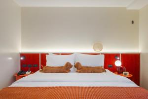 a bedroom with a large white bed with red walls at Lilybeth Hotel Pratunam in Bangkok