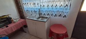 a small kitchen with a sink and a red stool at Kuils River Apartment, near Cape Town Airport in Sarepta