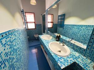 un bagno piastrellato blu con due lavandini e una vasca di Regina34 a Torre a Mare
