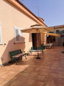 a patio with two benches and an umbrella at Casa di Agnese in Alghero