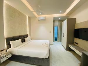 a bedroom with a white bed and a flat screen tv at Hotel Radhe Imperial in Hyderabad