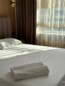 a towel on a white bed with a window at Улы дала in Shymkent