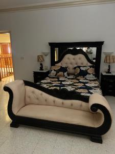 a bed with a couch in a bedroom at La villa jasmin in Al Maqārisah