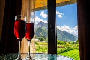 two glasses of wine sitting on a table in front of a window at Cottage Shina in Kazbegi +23 photos