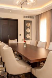 a dining room with a wooden table and white chairs at Lancaster Palace Tamuda Bay in Marina Smir +88 photos