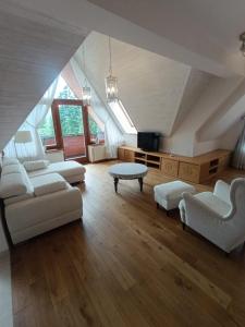 a large living room with white couches and a tv at Secret Residence with Sauna & Private Pool in Kościelisko