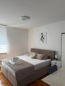 a white bedroom with a bed and a table at Emama Residence Mostar in Mostar