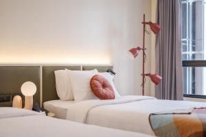 a hotel room with two beds with pink pillows at Lilybeth Hotel Pratunam in Bangkok