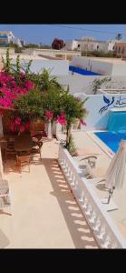 a patio with chairs and flowers and a swimming pool at La villa jasmin in Al Maqārisah