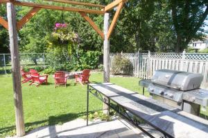 a grill in a backyard with chairs and a table at Gypsy by the Lake Bed and Breakfast in Sutton