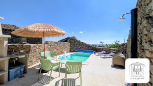 a patio with a table and chairs and an umbrella at Casa do Avô Gonçalo in Mogadouro