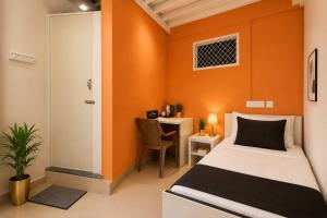 a small room with a bed and a desk at Leo Stays in Bangalore