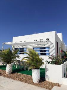 a white building with palm trees in front of it at Atardeceres casa de playa in Cartagena de Indias