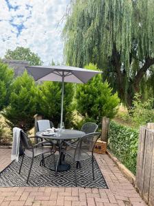 a table and chairs with an umbrella on a patio at The Willow Luxury Countryside Retreat in Stone