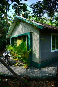 a small house with a motorcycle parked in front of it at CatsClaw Inn in Talayolaparambu