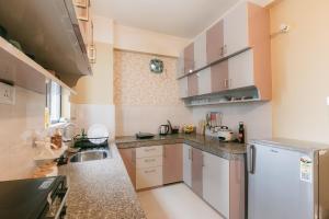 a kitchen with white cabinets and a white refrigerator at CueCasa in Guwahati