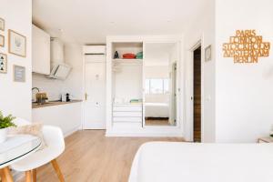 a white bedroom with a white bed and a kitchen at New Central Studio Torremolinos in Torremolinos