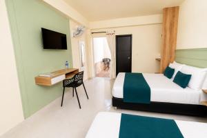 a bedroom with two beds and a desk and a television at Hotel Campestre Santa Catalina in San Gil