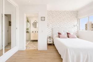 a white bedroom with a large white bed with pink pillows at New Central Studio Torremolinos in Torremolinos