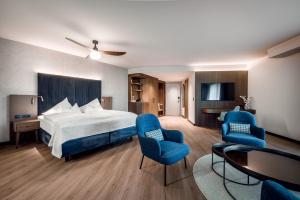 a hotel room with a bed and two blue chairs at Krumers Alpin – Your Mountain Oasis in Seefeld in Tirol +98 photos