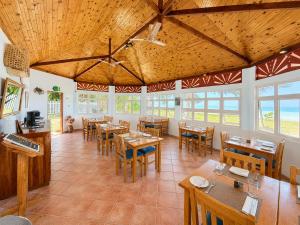 a dining room with wooden tables and chairs at Beach Villa Guesthouse in Grand Anse
