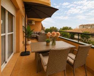 a table and chairs on a balcony with an umbrella at BlueSabinillas in San Luis de Sabinillas