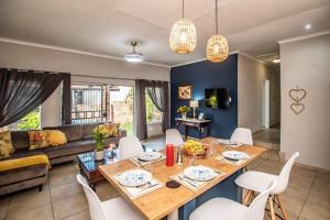 a living room with a wooden table and white chairs at Dew Drop Inn in Nelspruit