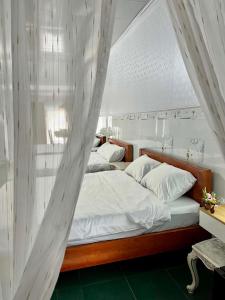 a bedroom with two beds with white sheets at Cát Home in Phú Hiệp