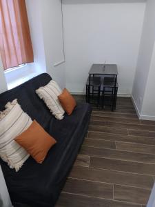 a black couch with pillows and a table in a room at Joli t1 bis Drôme des collines in Saint-Vallier