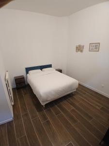 a bedroom with a white bed and a wooden floor at Joli t1 bis Drôme des collines in Saint-Vallier