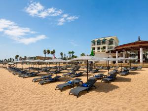 a bunch of chairs and umbrellas on a beach at Lancaster Palace Tamuda Bay in Marina Smir