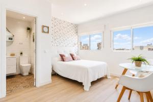 a white bedroom with a bed and a table at New Central Studio Torremolinos in Torremolinos