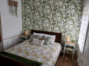 a bedroom with a bed with a floral wallpaper at Les 4 Portes in Le Mesnillard