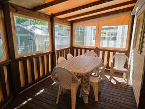 a table and chairs on a screened in porch at Camping les sables in Aytré